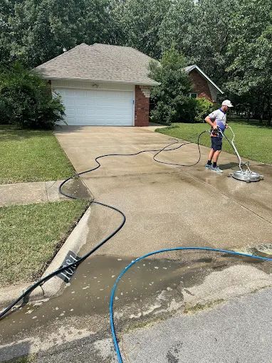 Worker running a rotary surface cleaner over a concrete driveway in Springfield MO