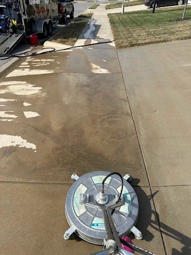 Rotary surface cleaner part-way across a concrete driveway showing the clean line
