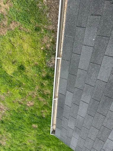 Cleared gutter and roof edge above a green lawn